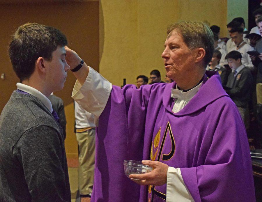 Fr. John Jimenez traces the sign of the cross on a student’s forehead for Ash Wednesday.
