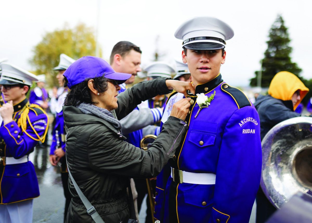 Andreas Flores Fok ’24 is assisted by his mother before a band review.