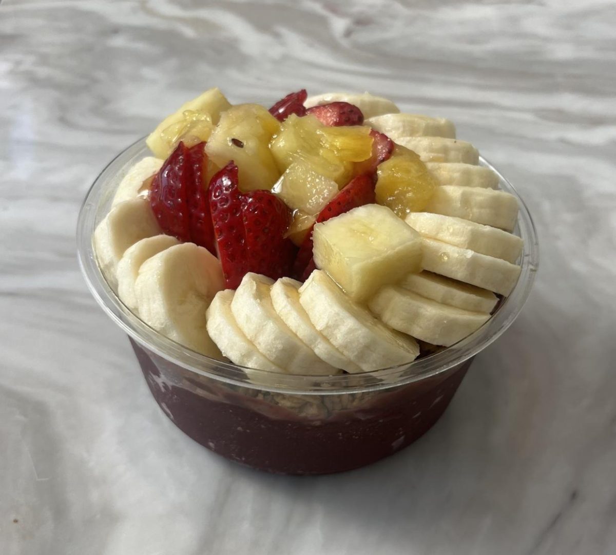 A fresh açaí bowl resting on a marble counter, laden with an array of fruit.