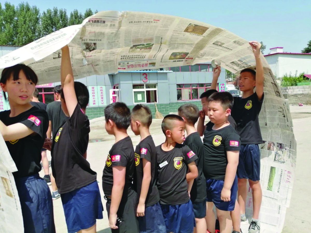 Students use a newspaper to shield themselves from humidity in Beijing.
