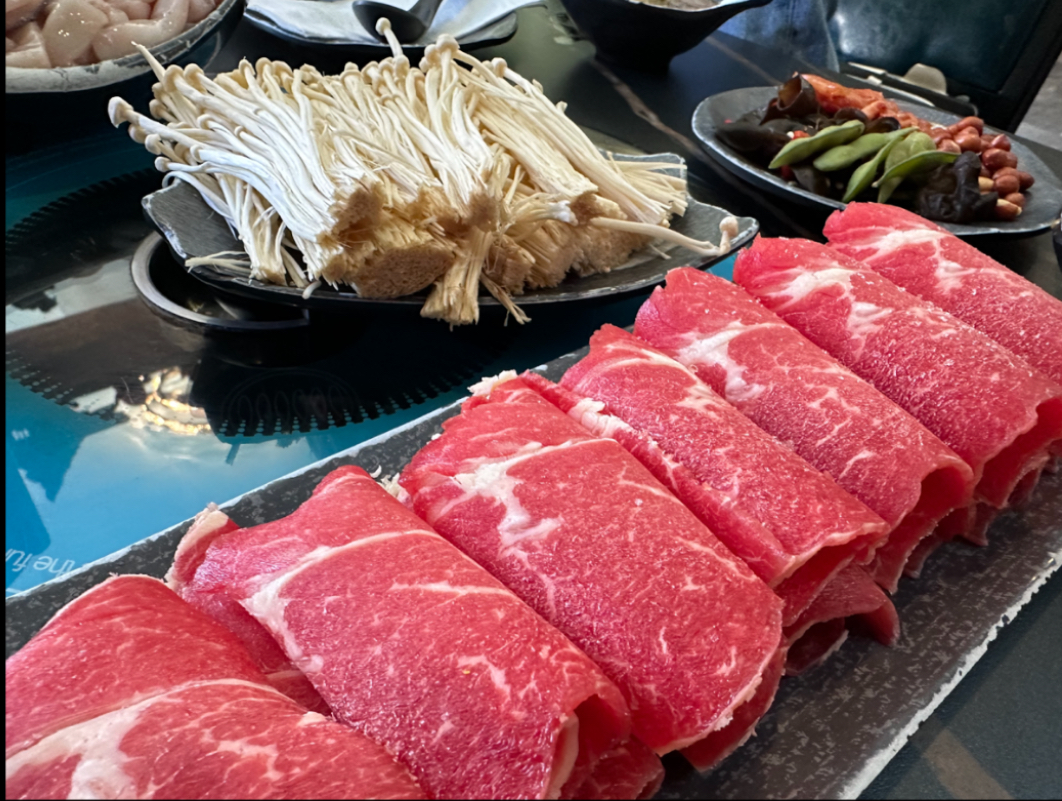 Rolled meat in uniform formation accompanied by enoki mushrooms.