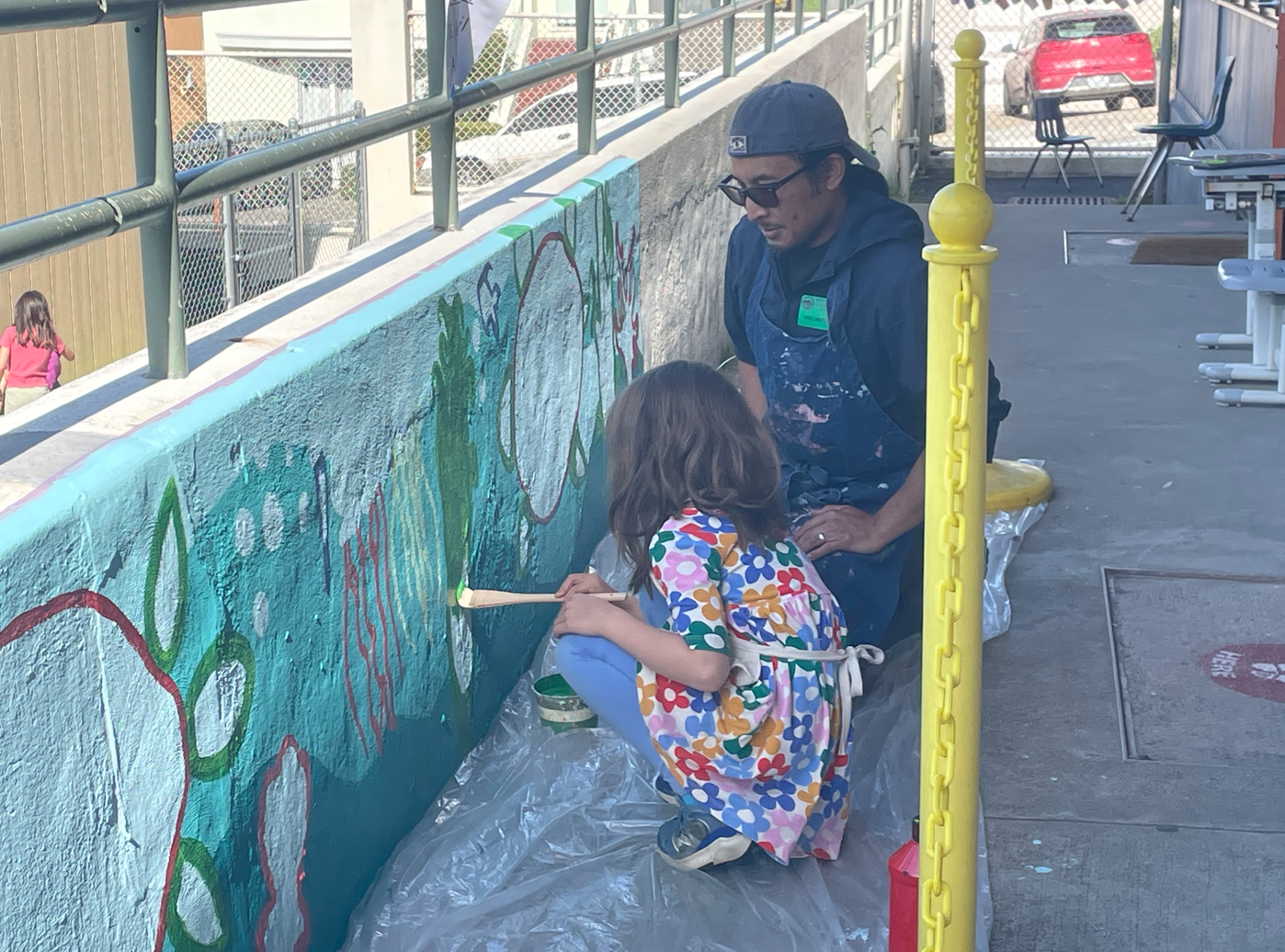 Over spring break, members of the Art Club painted a marine-themed mural outside a kindergarten classroom at West Portal Elementary School. Here, Irman Arcibal assists a kindergartner with the mural as she paints in seaweed.