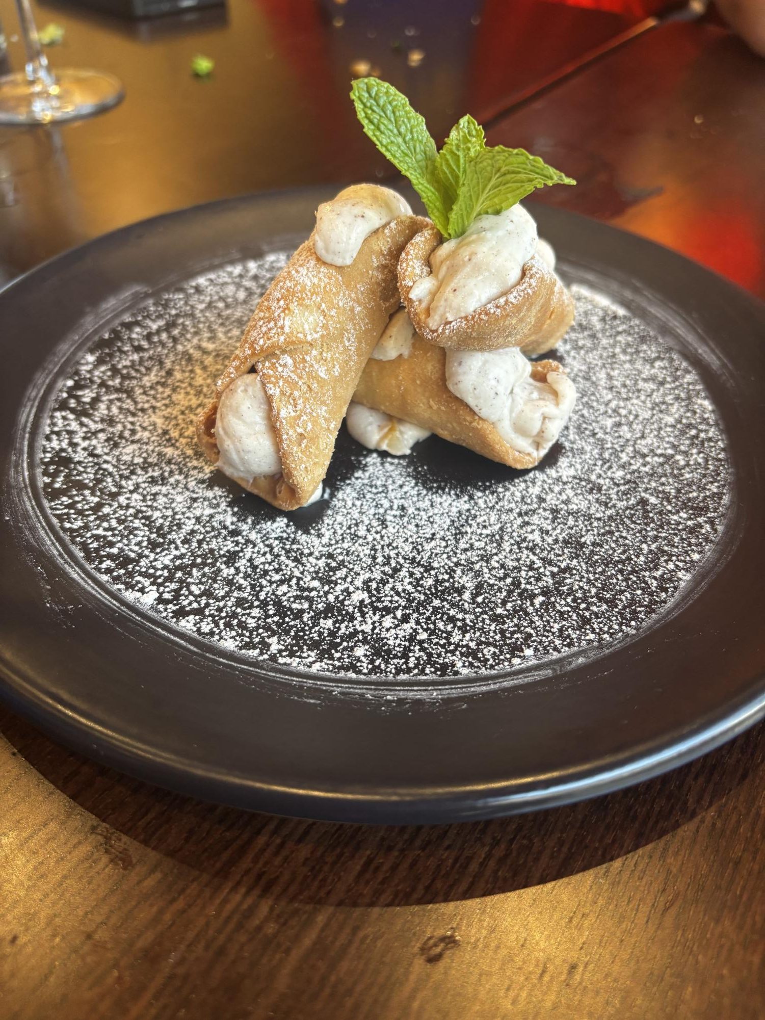 From Steps of Rome Trattoria: three warm cannoli stacked on top of each
other, and garnished with powdered sugar and a bundle of fresh mint.