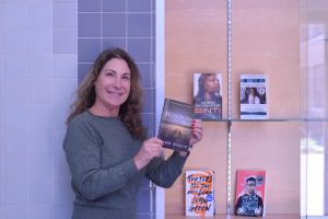 Dean of Academics Diana Assereto places this year's summer reading book in the summer reading case.