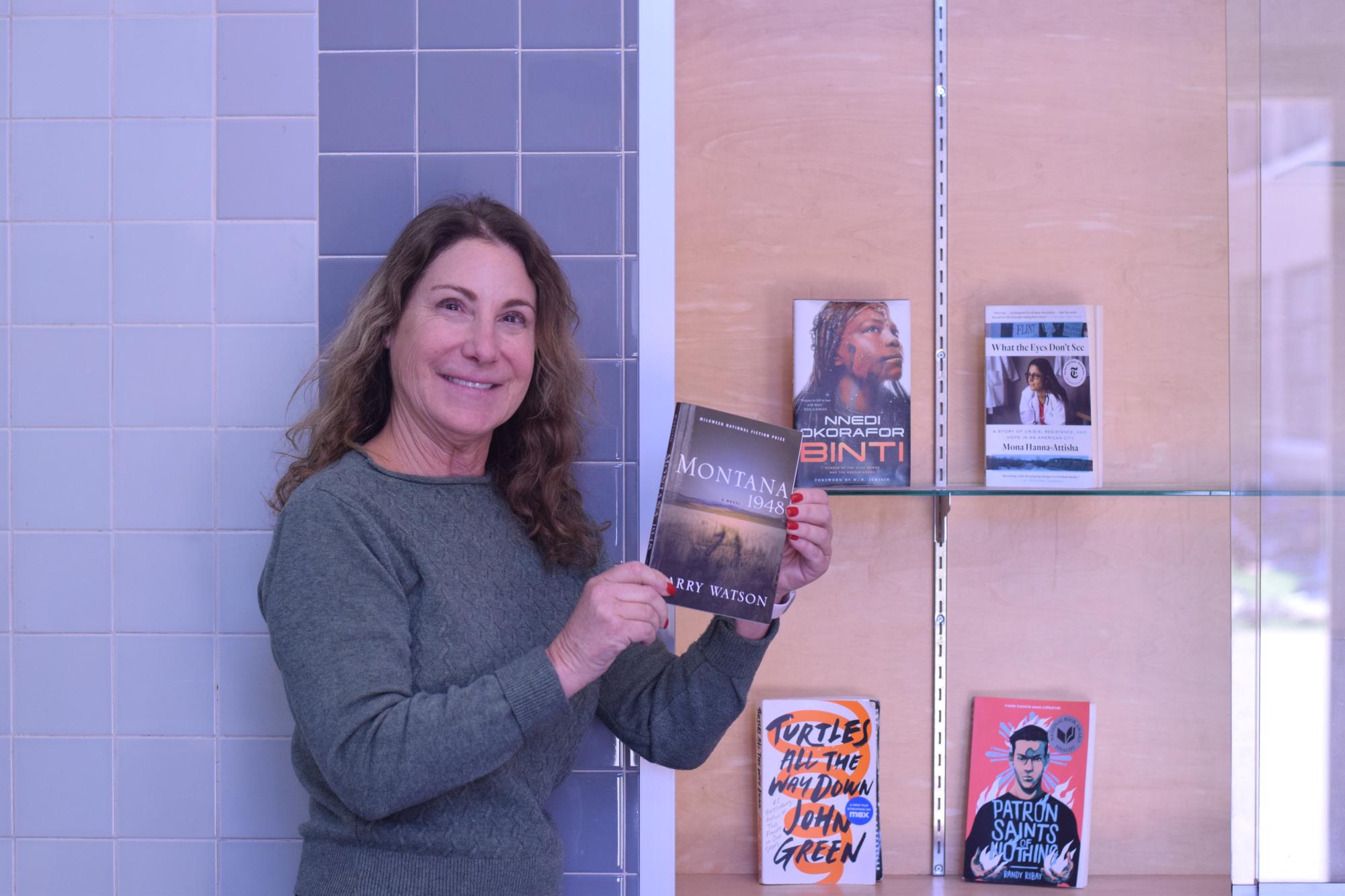 Dean of Academics Diana Assereto places this year's summer reading book in the summer reading case. 